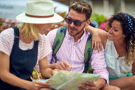 Group of friends are watching the map while while planning a day during a holiday on a beautiful day on the seaside. Vacation, friendship, seasideの写真素材