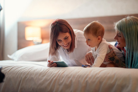Lesbian couple cuddling with their baby in the bed