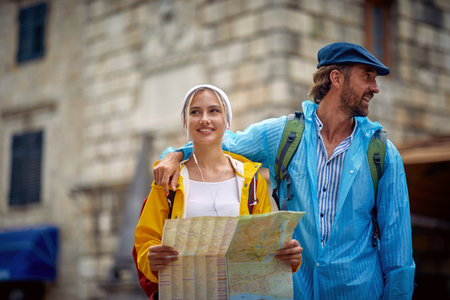 Summertime rain. Young couple on walk in city. Joyful man and woman on holiday. Travel,...