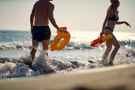A young couple enjoys playing with toys in the shallow on the beach on a beautiful summer day. Summer, beach, sea, vacationの写真素材