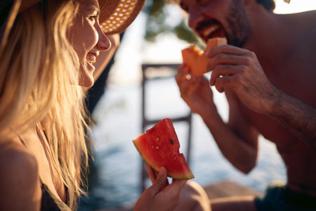 Close up portrait shot of couple enjoying melon fruit together. Summer vacation by sea. Holiday, togetherness, lifestyle concept.の写真素材