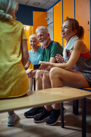 Senior couple talking with friends. Group of four people in gym dressing room after workout. Senior life concept.の写真素材