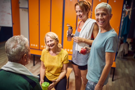Fitness is life. Joyful senior woman in sportswear standing and smiling, feeling blissful after workout with friends in dressing room.の写真素材