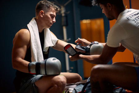 Young boxing player preparing for boxing workout, coach helping him put on boxing gloves. Sports, lifestyle, martial arts concept.の写真素材
