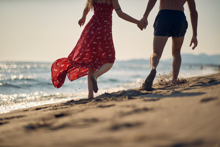 A young couple enjoying a walk on the beach on a beautiful summer day. Summer, beach, sea, vacationの写真素材