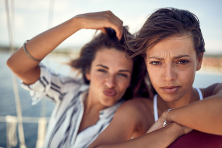 Close-up of two handsome female models who is posing for a photo on a beautiful sunny day on a yacht. Summer, sea, vacation, friendshipの写真素材