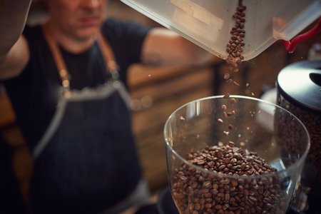 caucasian man putting roasted whole grain coffee from plastic dish into bowl of glass