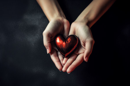 Female hands holding a red heart on a dark background. Valentine's Dayの素材