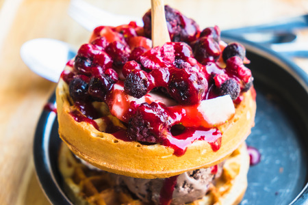 waffles and chocolate icecream with fresh berries on wooden trayの写真素材