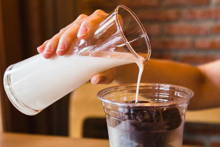 Fresh milk pouring into glass with frozen chocolateの写真素材