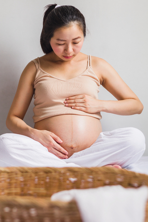 Asian pregnant women sitting on bedの写真素材
