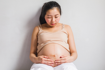 Asian pregnant women sitting on bedの写真素材