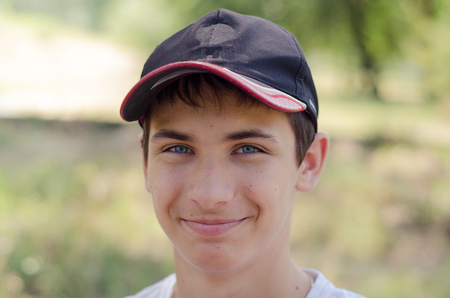 Close up portrait of a cute teenager in a baseball cap with blue eyes. Outdoors.の写真素材