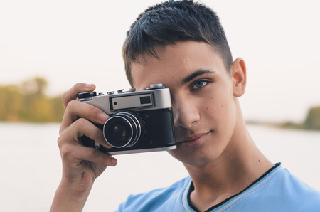Cute boy teenager with vintage rangefinder camera. Close-up Photo.
