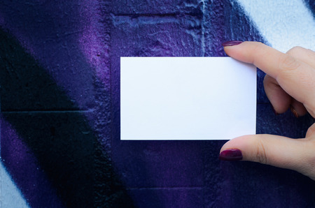 Female hand holding blank white business card over colorful background.の写真素材