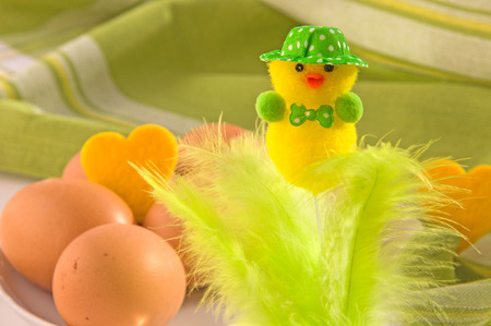 Easter decoration (cute neatly hatted chicken with bow tie) and eggs on cotton napkin. Main colors:...