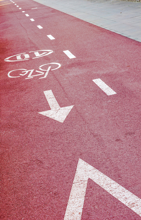 Bike path with white symbol of bike, speed limit sign, arrow and broken line on a cycling path. Vertical.の写真素材
