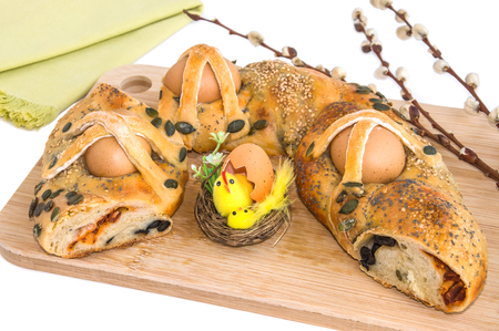 Traditional holiday pie with eggs, Easter decoration and willow branches on wooden cutting board. Horizontal, white background.の写真素材