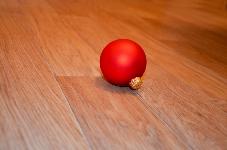 One red christmas tree ball on the wooden floorの写真素材