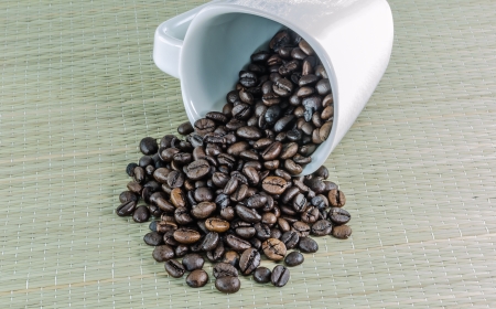 Coffee beans in white glass falling on the floor mat の写真素材