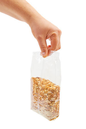 Oatmeal flakes into hand. Isolated on a white background.の写真素材