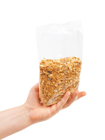 Oatmeal flakes into hand. Isolated on a white background.の写真素材