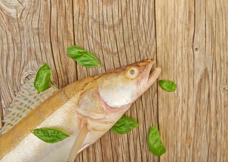 Fish perch on a wooden table and basil leavesの写真素材