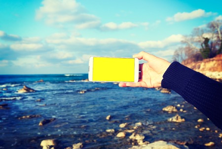 White smart phone on the background Black Sea in female hands, effect