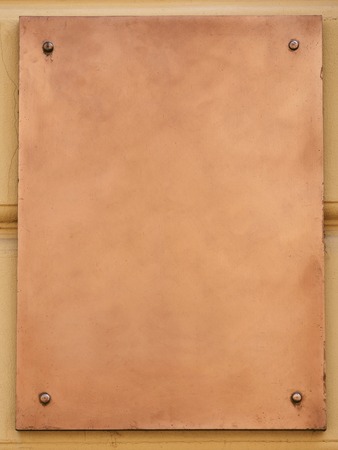 Old brass yellow metal plate framed and nailed on stone wall backgroundの写真素材