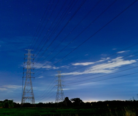 Electric high voltage power post in the night and beautiful stars.の写真素材