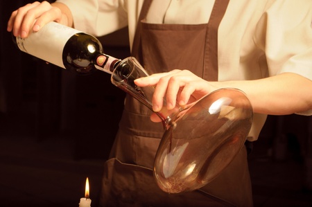 A sommelier pouring red wine into decantorの写真素材