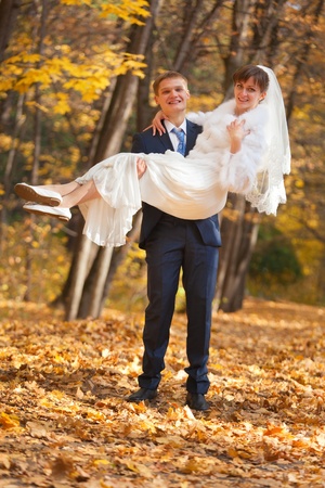 Groom carries bride in his arms - outdoor shotの写真素材
