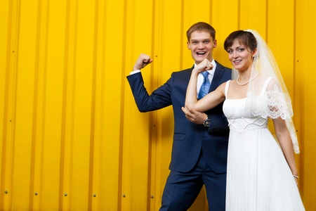 Happy Bride and groom posing against yellow wallの写真素材