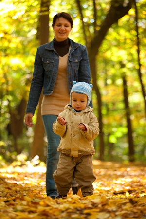 Happy young mother and her little sun in an autumn parkの写真素材
