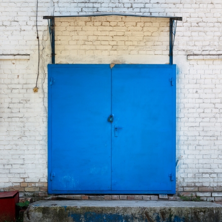 Metall painted blue door on the whitewashed wallの写真素材