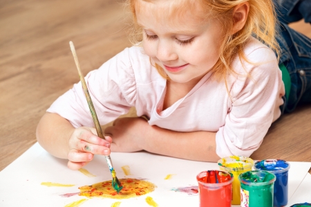 Cute little redhead girl painting with brush.の写真素材