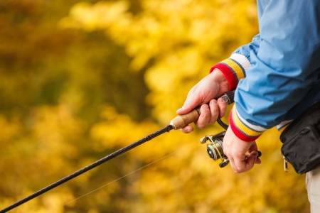 Closeup of Fisherman`s hand with spinning - autumn fishing season.