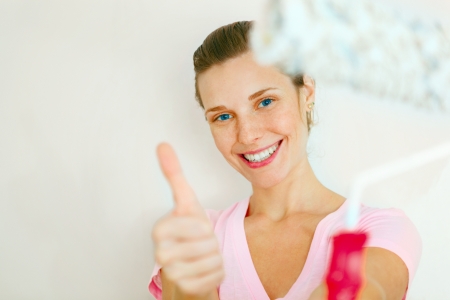 Young Happy Woman showing thumb up with roller brush の写真素材
