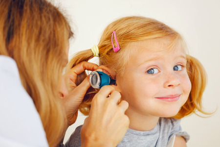 Pediatrician doctor examining little girl`s ears.の写真素材