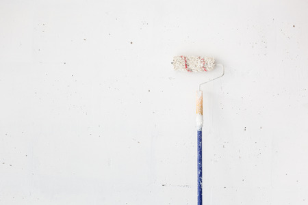 Roller brush with stick lean on white wall.の写真素材
