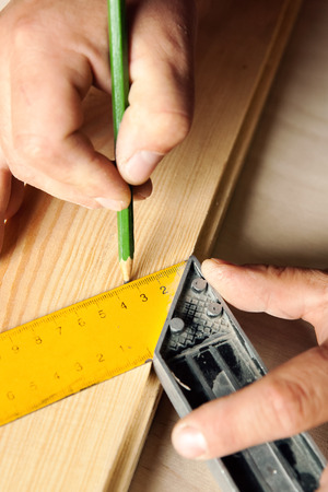 Male hands with ruler and pencil closeup. Proffesional carpenter at work.の写真素材