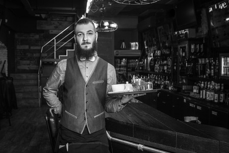 Handsome waiter in a restaurant with tray. Black and white edit.の写真素材