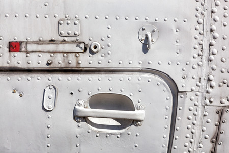 Old white painted aircraft fuselage close up. Door handle and rivets.
