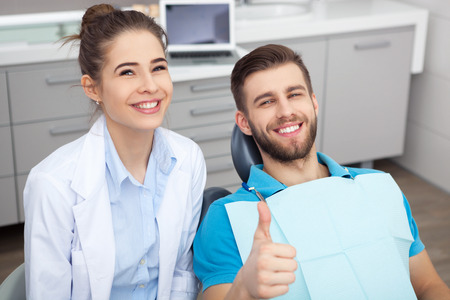 Portrait of a young man sitting in a dentist's chair giving a thumbs up.の写真素材
