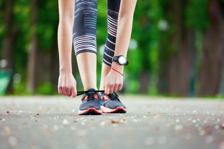 Shot of a young woman tying her laces before a run.