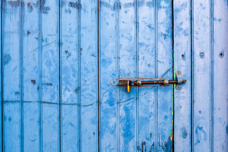 Close up of an old painted blue door with door bolt.