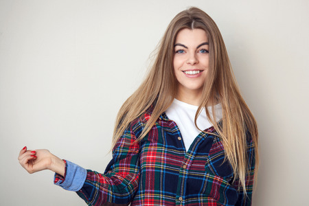 Studio portrait of happy young woman in plaid shirt posing against wall.の写真素材