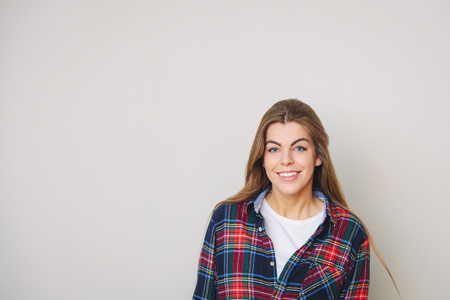 Studio portrait of happy young woman in plaid shirt posing against wall.の写真素材
