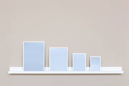 Close up of white shelf with picture frames on wall.