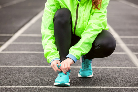 Cropped shot of a woman tying her shoelaces before running on a stadium.